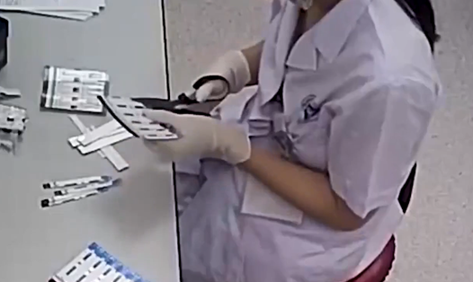 Nhân viên y tế cắt đôi que thử xét nghiệm. Ảnh chụp màn hình từ phóng sự điều tra của VTV24
