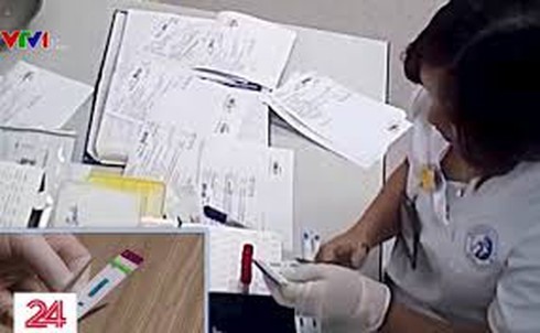 Hình ảnh nhân viên y tế cắt đôi que thử HIV, viêm gan B do VTV24 ghi lại.