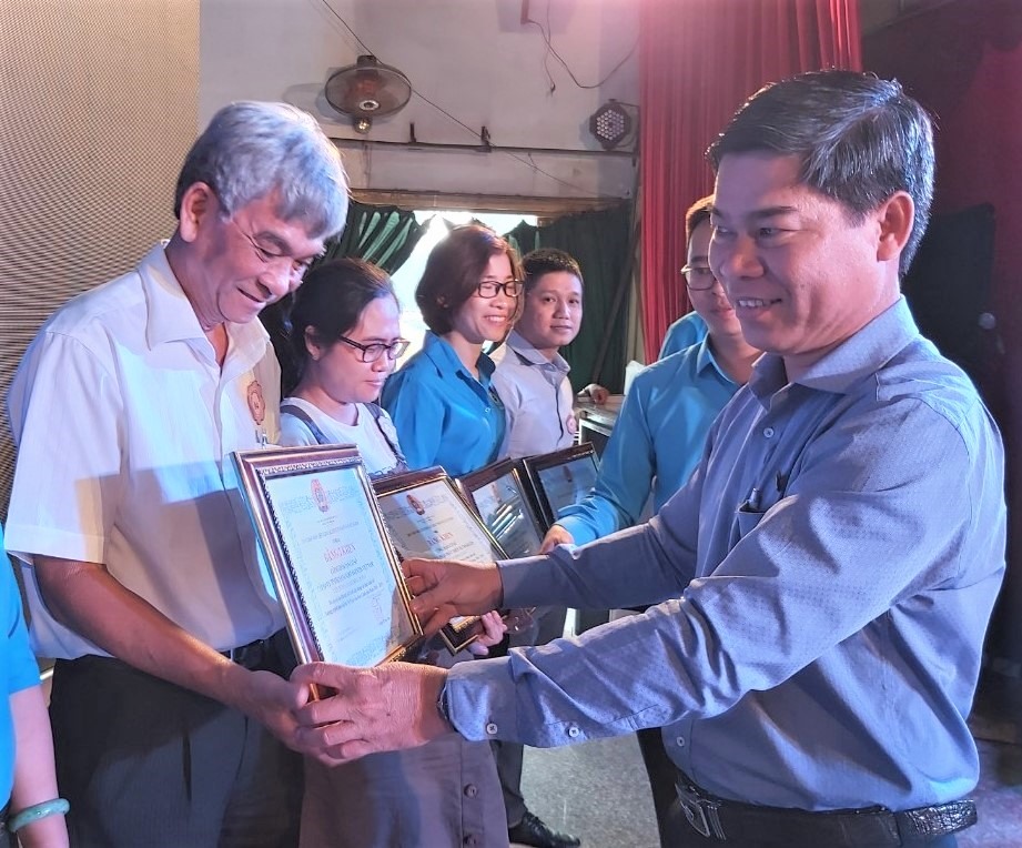 Ông Phạm Chí Tâm (bìa phải), Phó Chủ tịch LĐLĐ TP.Hồ Chí Minh trao Bằng khen của LĐLĐ TP.Hồ Chí Minh cho các tập thể có nhiều thành tích trong Chương trình học bổng Nguyễn Đức Cảnh. Ảnh Nam Dương