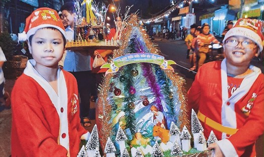Hai em bé mặc đồ ông già Noel rước lễ vật ở khu xóm đạo, quận 8 (Ảnh: Phạm Thế Hiển)