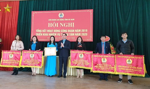 Chủ tịch Tổng LĐLĐVN Nguyễn Đình Khang trao Cờ thi đua xuất sắc cho các đơn vị của LĐLĐ tỉnh Hà Nam. 
Ảnh: Thu Lệ