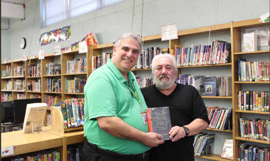 Ông Harry Krame (bên trái) và cán bộ thư viện trường Memorial hiện tại đang đứng chụp hình chung cùng cuốn sách "The Family Book Of Verse”.