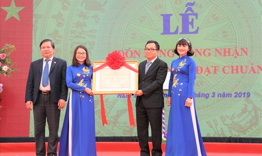 Cô Nguyễn Thị Lý đại diện cho giáo viên và học sinh của nhà trường nhận bằng công nhận Trường THCS Nguyễn Du đạt chuẩn quốc gia.