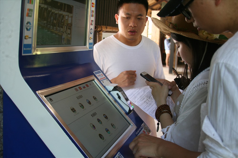 Du khách mua vé tự động tại máy bán vé tự động đặt ở Suối khoáng nóng I-resort. Ảnh: K.L