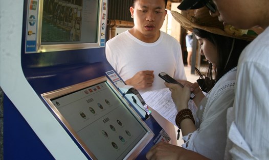 Du khách mua vé tự động tại máy bán vé tự động đặt ở Suối khoáng nóng I-resort. Ảnh: K.L