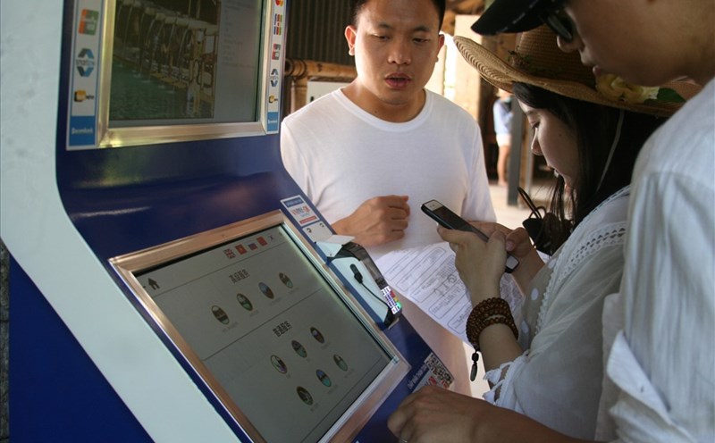 Du khách mua vé tự động tại máy bán vé tự động đặt ở Suối khoáng nóng I-resort. Ảnh: K.L