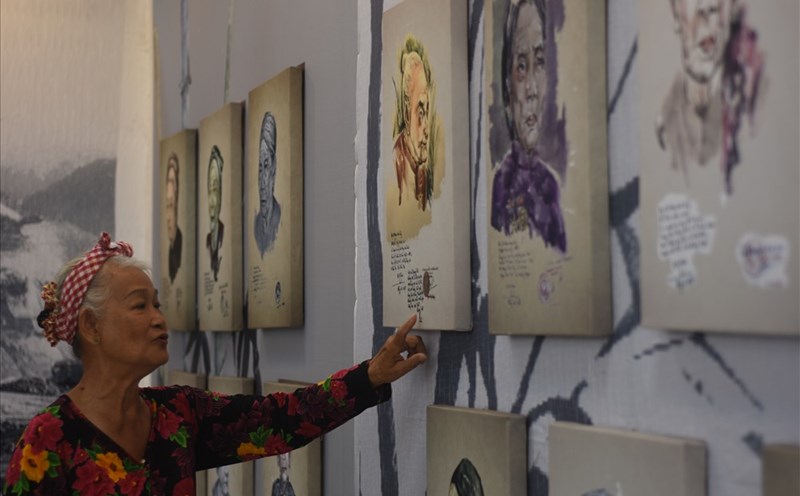 Họa sĩ Đặng Ái Việt giới thiệu những chân dung Bà mẹ Việt Nam anh hùng đến đại biểu tham dự triển lãm.