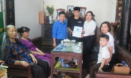Đại diện Trung tâm truyền thông (BHXH Việt Nam) trao tặng thẻ BHYT cho con chị Lê Thị Thu Hà. Ảnh: BHXH Việt Nam