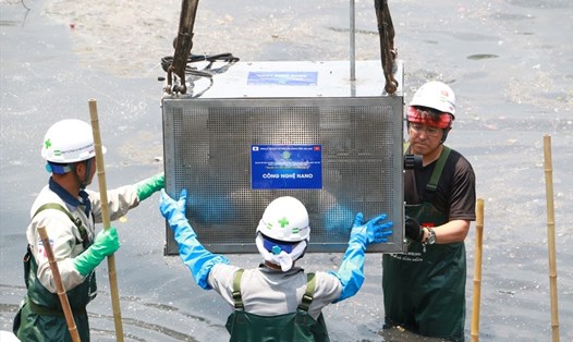 Các kỹ sư và công nhân hạ thiết bị xử lý ô nhiễm xuống sông Tô Lịch. Ảnh PV