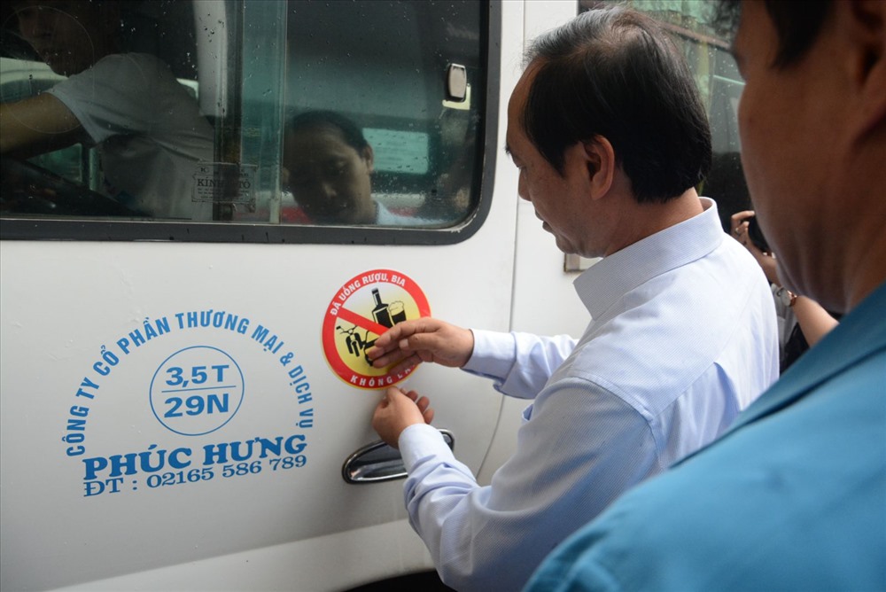 Thứ trưởng Bộ GTVT Lê Đình Thọ dán lô gô tuyên truyền lên xe khách
tại bến xe Mỹ Đình. Ảnh: T.T