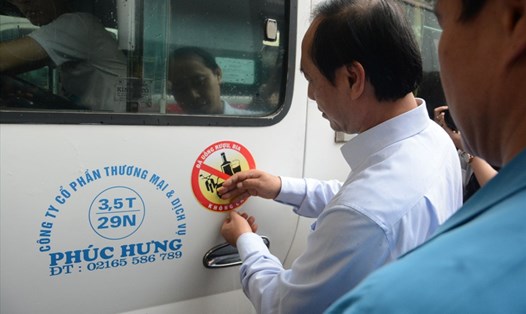 Thứ trưởng Bộ GTVT Lê Đình Thọ dán lô gô tuyên truyền lên xe khách
tại bến xe Mỹ Đình. Ảnh: T.T