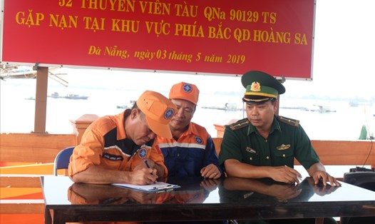 Cơ quan chức năng đang ký biên bản bàn giao thuyền viên và tàu cá bị nạn cho cơ quan chức năng.