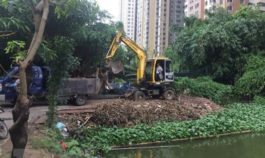 UBND phường Trung Văn tổ chức phương tiện để xúc những phần vật liệu đổ trộm tại hồ Ngòi. (Ảnh: Nguyễn Thắng/TTXVN)