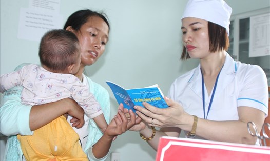Cán bộ y tế xã Thượng Sơn- Vị Xuyên- Hà Giang kiểm tra sổ tiêm chủng trước khi tiêm vắc xin cho trẻ. Ảnh: Thùy Linh