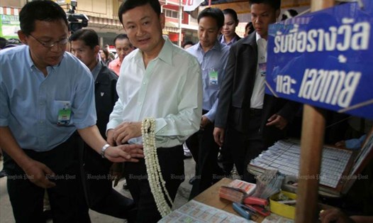 Ông Thaksin Shinawatra khi đó còn là Thủ tướng Thái Lan đi qua một quầy bán xổ số của chính phủ ở tỉnh Tak năm 2004. Ảnh: Bangkok Post.