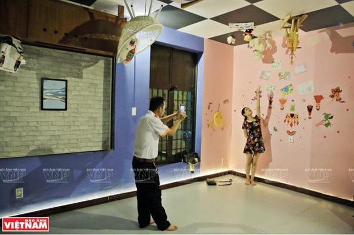 Du khách thích thú chụp hình cùng những bài trí lộn ngược lạ mắt bên trong nhà. Ảnh VNplus