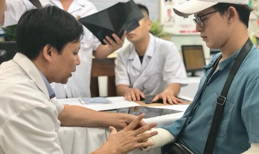 Diễn viên Quang Anh (vai Bảo trong phim "Về nhà đi con") được các bác sĩ Bệnh viện Hữu nghị Việt Đức thăm khám tay đêm 23.7. Ảnh: NH
