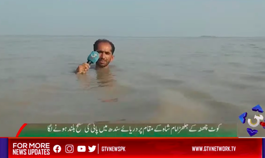 Phóng viên Azadar Hussain ngâm mình trong nước lũ ngập tới cổ để đưa tin. Ảnh: RT.