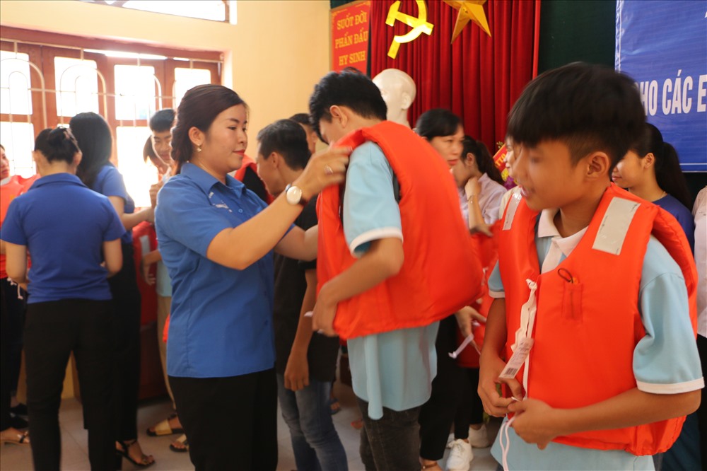 Cán bộ, đoàn viên của LĐLĐ tỉnh Hòa Bình hướng dẫn các em học sinh mặc áo phao.
