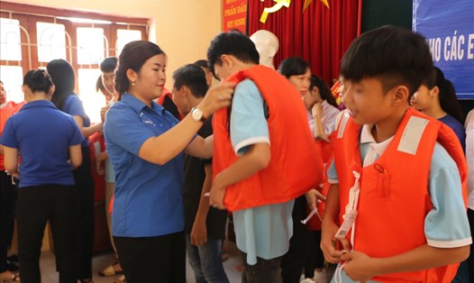Cán bộ, đoàn viên của LĐLĐ tỉnh Hòa Bình hướng dẫn các em học sinh mặc áo phao.