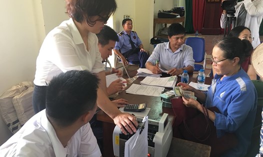Một số hộ dân xã Nam Sơn đến Nhà văn hóa thôn Xuân Bảng nhận tiền đền bù đất ruộng. Ảnh PV.