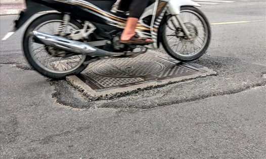 Nắp cống nhô cao hơn mặt đường và xuất hiện ổ gà gây nguy hiểm cho người chạy xe máy trên đường Trường Sa.  Ảnh: M.Q