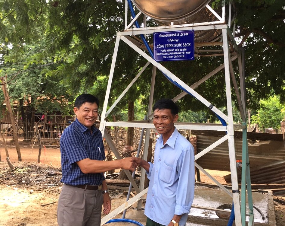 Đồng chí Nguyễn Xuân Nghĩa - Chủ tịch CĐCS xã Lộc Hòa (bên trái) chúc mừng gia đình đoàn viên được nhận công trình nước sạch.