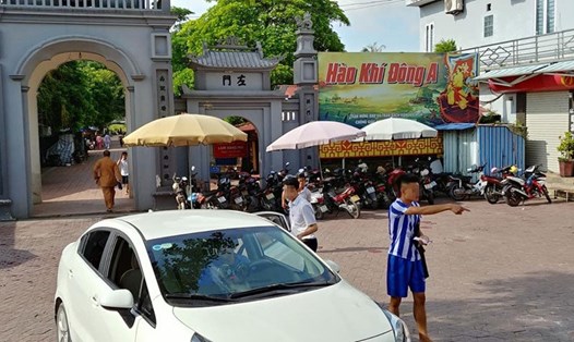 Đối tượng "chặt chém" tiền dừng, đỗ xe trước cổng đền mặc áo kẻ. Ảnh: Hoàng Minh Huy