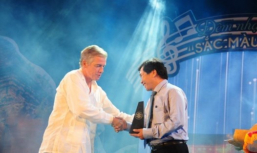 Đại diện Tạp chí Travel & Leisure (bìa trái) trao biểu tượng danh hiệu cho lãnh đạo TP.Hội An