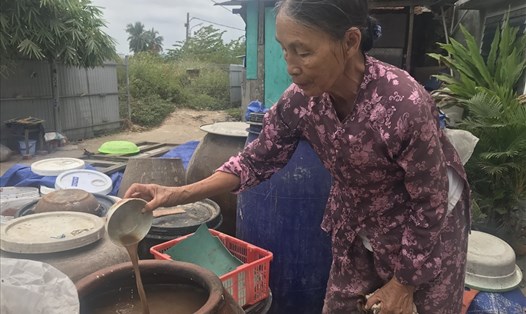 Bà Nguyễn Thị Lự (phường Hòa Hiệp Nam, quận Liên Chiểu) - người có hơn 50 năm làm nghề nước mắm Nam Ô - bên chum nước mắm đang ủ. Ảnh: H.Vinh
