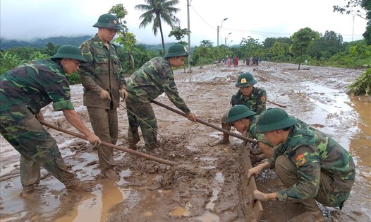 Lực lượng Biên phòng Quảng Trị hỗ trợ người dân cào lớp bùn do mưa lũ để lại trên đường. Ảnh: HƯNG THƠ