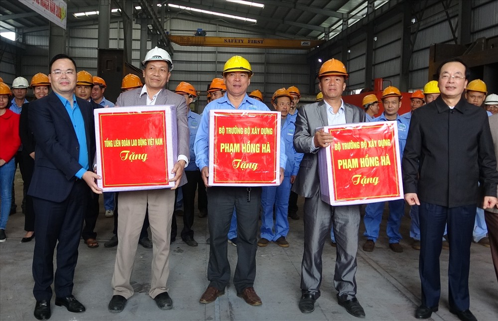 Đồng chí Phạm Hồng Hà, Ủy viên Trung ương Đảng, Bộ trưởng Bộ Xây dựng (ngoài cùng bên phải) và đồng chí Trần Văn Khải, Ủy viên Đoàn Chủ tịch, Trưởng ban Quản lý Dự án Thiết chế Công đoàn (Tổng Liên đoàn Lao động Việt Nam) (ngoài cùng bên trái) trao quà tới công nhân lao động.