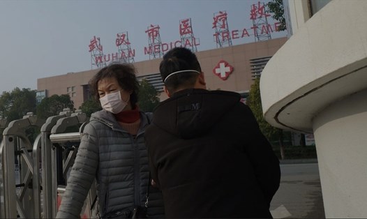 Người phụ nữ đứng trước cơ sở Y tế ở Vũ Hán, nơi có trường hợp đầu tiên tử vong do nhiễm coronavirus. Ảnh: AFP