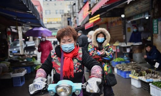 Một phụ nữ đi qua một khu chợ ở Vũ Hán hôm 24.1. Ảnh: AFP.