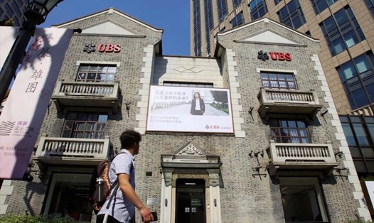 Một người đàn ông đi ngang qua trụ sở ngân hàng Thuỵ Sĩ UBS ở Thượng Hải, Trung Quốc. Ảnh: Reuters
