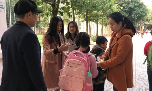 Giáo viên Trường Tiểu học Lý Thái Tổ tiến hành sát khuẩn tay và đo thân nhiệt cho học sinh trước khi vào trường. Ảnh: V.L