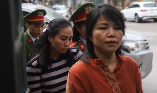 Bà Nguyễn Thị Vững (áo cam) và Nguyễn Thị Vân (áo kẻ, phía sau) bị dẫn giải vào phòng xử án.