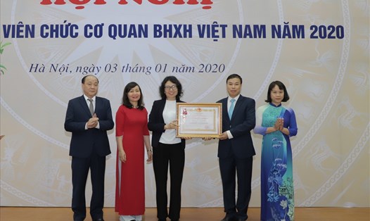 Tổng Giám đốc BHXH Việt Nam Nguyễn Thị Minh (thứ ba từ trái sang) trao Huân chương Lao Động hạng Nhất cho 
Ban Thực hiện chính sách BHXH. Ảnh: Thanh Hằng