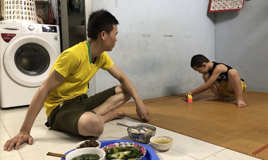 Anh Bùi Văn Chung đang dỗ dành con trai ăn tối. Ảnh: Quỳnh - Hân