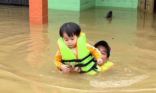 Cứu hộ một em nhỏ ra khỏi dòng nước lũ tại huyện Quảng Ninh. Ảnh: CTV