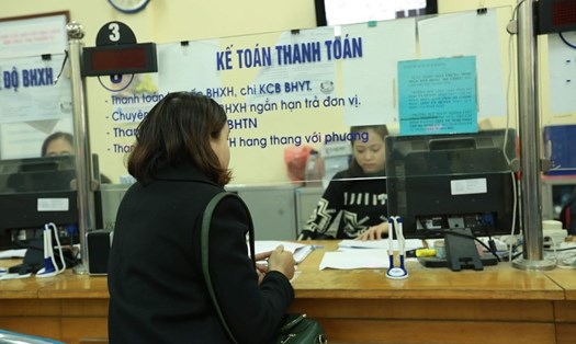 Cán bộ Bảo hiểm xã hội quận Cầu Giấy (Hà Nội) hướng dẫn người dân hoàn thiện hồ sơ bảo hiểm y tế. Ảnh: Nam Nguyễn