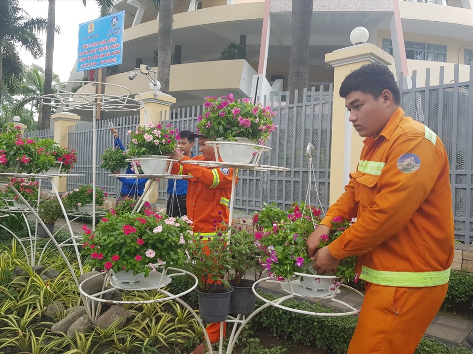 Nhân viên Công ty TNHH MTV Dịch vụ Công ích Quận 5 gắn các giỏ hoa do CNVLĐ quận đóng góp làm đẹp tuyến dường An Dương Vương. Ảnh Đức Long