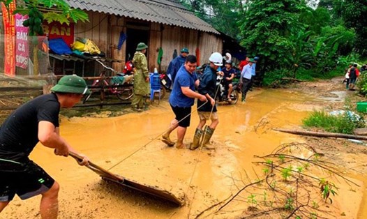 Lực lượng cứu hộ giúp người dân dọn dẹp nhà ở bị bùn đất tràn vào để ổn định cuộc sống. Ảnh: Quốc Hồng