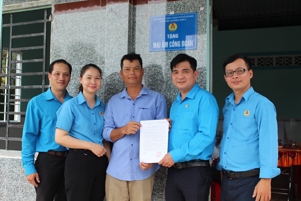Ông Nguyễn Trọng Nghĩa - Chủ tịch LĐLĐ quận 8 (thứ hai từ phải qua), trao Quyết định tặng "Mái ấm Công đoàn" cho anh Phạm Minh Hùng (giữa). Ảnh: Đức Long.