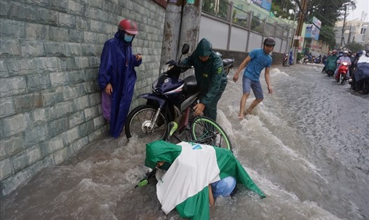 Chiều 24.9, mưa lớn khiến đường Võ Văn Ngân (quận Thủ Đức, TPHCM) nước chảy xiết, 2 người đi đường bị sụp hố ga nhưng may mắn được người dân cứu thoát trong gang tấc. Ảnh: Minh Quân