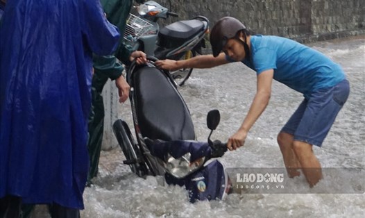 Xe máy người dân bị sụp hố ga trên đường Võ Văn Ngân trong mưa lớn chiều ngày 24.9. Ảnh: Minh Quân