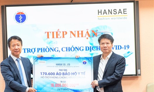 Thứ trưởng Bộ Y tế Trương Quốc Cường (bên phải) tiếp nhận biển tượng trưng 170.600 áo bảo hộ y tế phòng dịch COVID-19 do tập đoàn Hansae trao tặng. Ảnh Đức Long