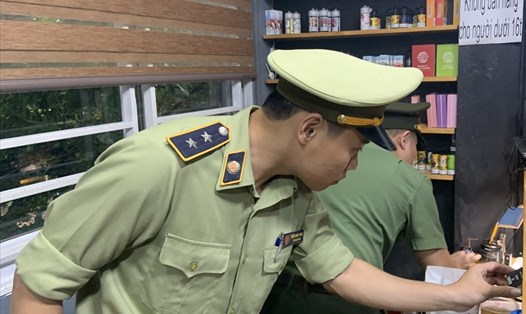 Lực lượng chức năng tiến hành kiểm tra hàng hóa tại cơ sở kinh doanh thuốc lá điện tử nhập lậu. Ảnh: Bình An