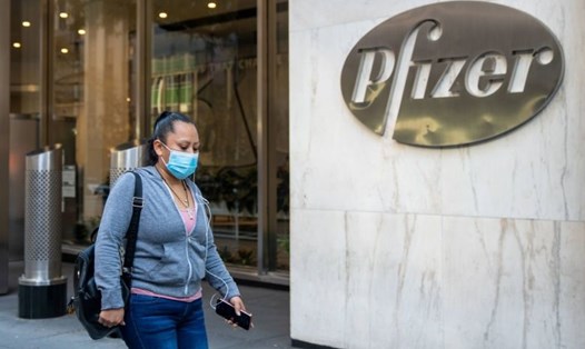 Một người phụ nữ đi ngang qua trụ sở của Pfizer ở New York, Mỹ. Hãng dược này đang phát triển vaccine COVID-19 có hiệu quả ngừa COVID-19 tới 90% nhưng cần bảo quản nhiệt độ siêu lạnh. Ảnh: AFP.
