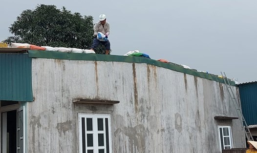 Ngoài chủ động sơ tán, chiều ngày 14 nhiều người dân ở tỉnh Hà Tĩnh còn dùng bao tải chứa cát để đè lên mái tôn phòng bão số 13 tốc mái nhà. Ảnh: TT.